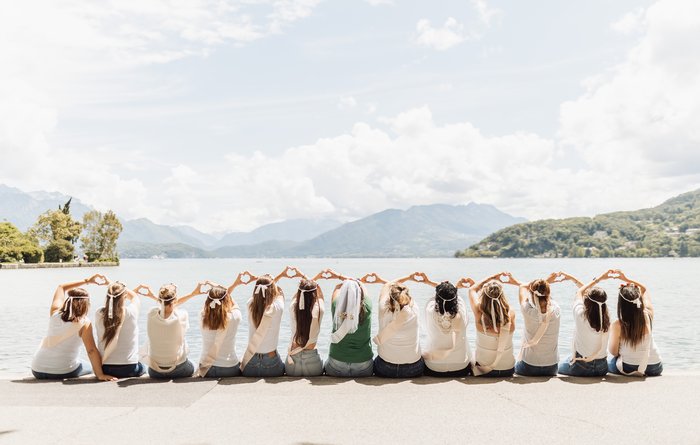EVJF à Annecy au bord du lac, groupe de filles formant un cœur avec les bras devant le paysage alpin