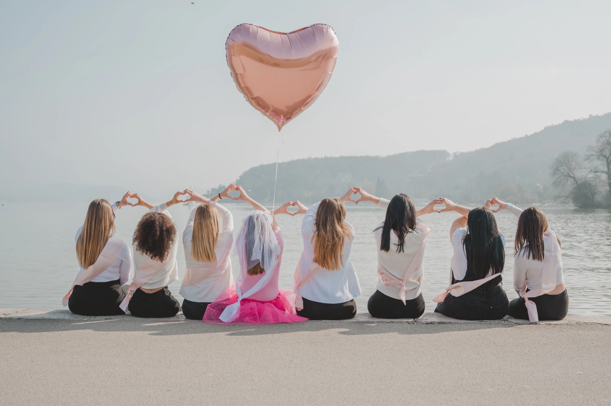 coeurs-dos-evjf-annecy-ballon Filles de dos faisant un cœur avec leurs mains devant le lac d’Annecy
