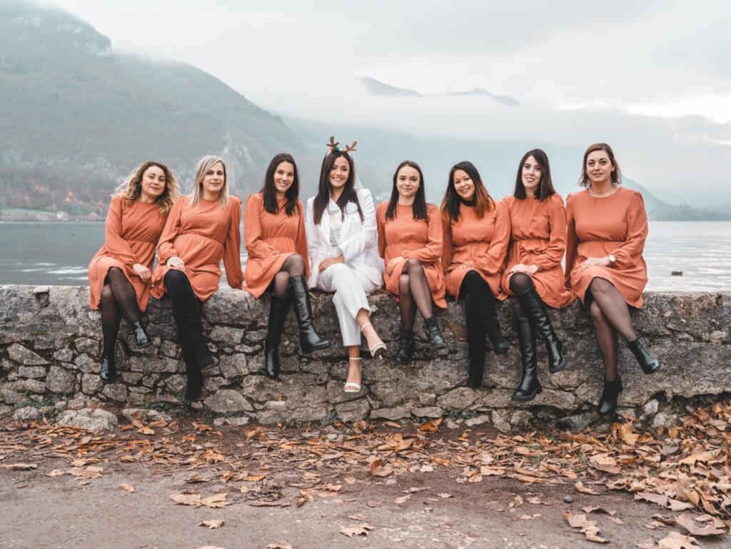 shooting photo evjf annecy - my little evjf Photo EVJF à Annecy sur un ponton au bord du lac, avec toutes les participantes en robe orange et la mariée en blanc