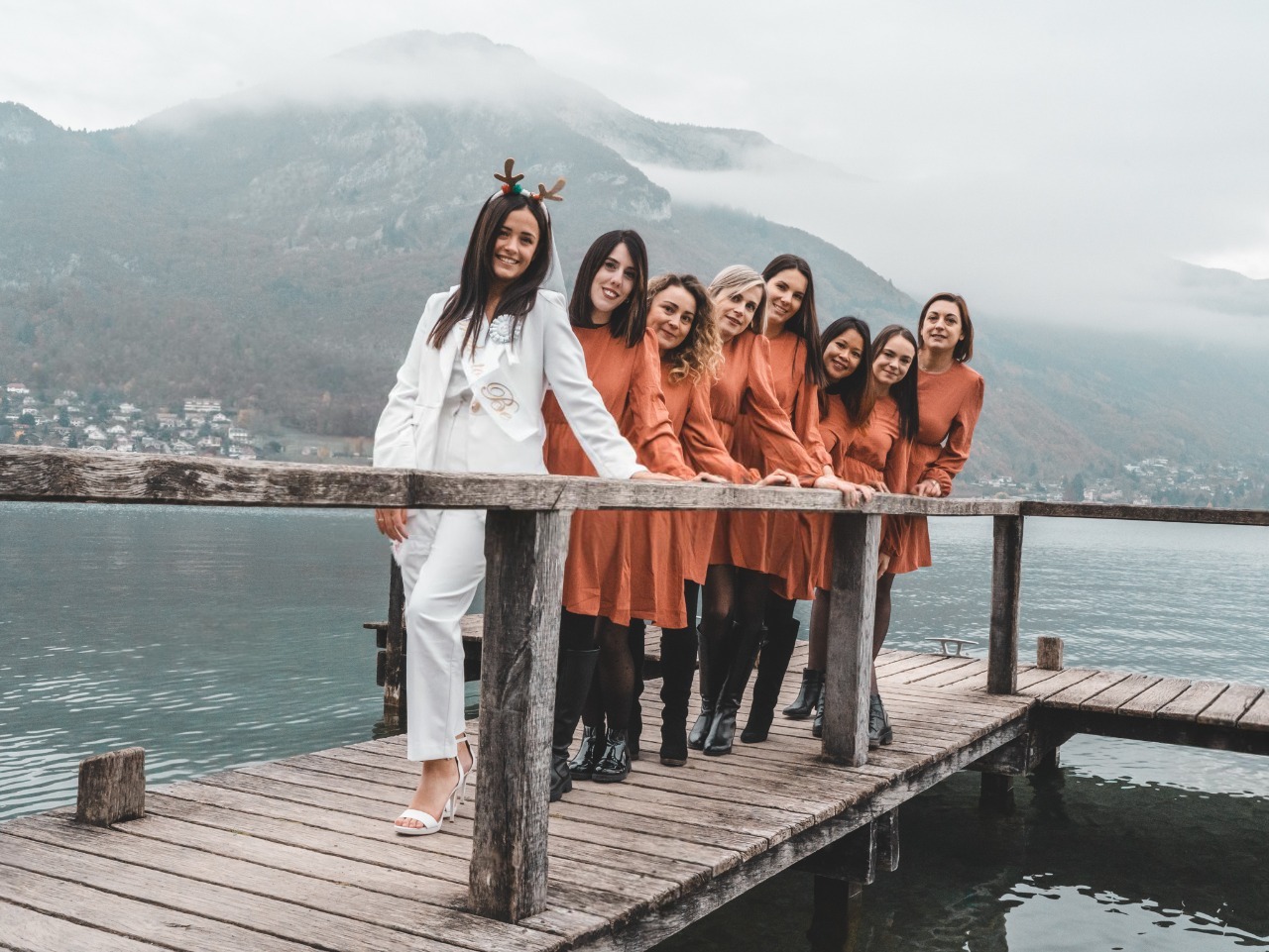 evjf-annecy-photo-fun-ponton Photo de groupe des participantes alignées sur un ponton en bois avec les montagnes en arrière-plan