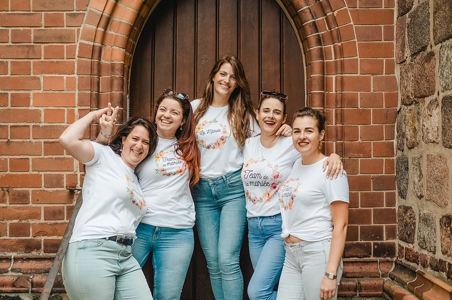 Enterrement de vie de jeune fille à Berlin – photo de groupe devant une porte en briques, t-shirts personnalisés "Team de la mariée", ambiance joyeuse et complice