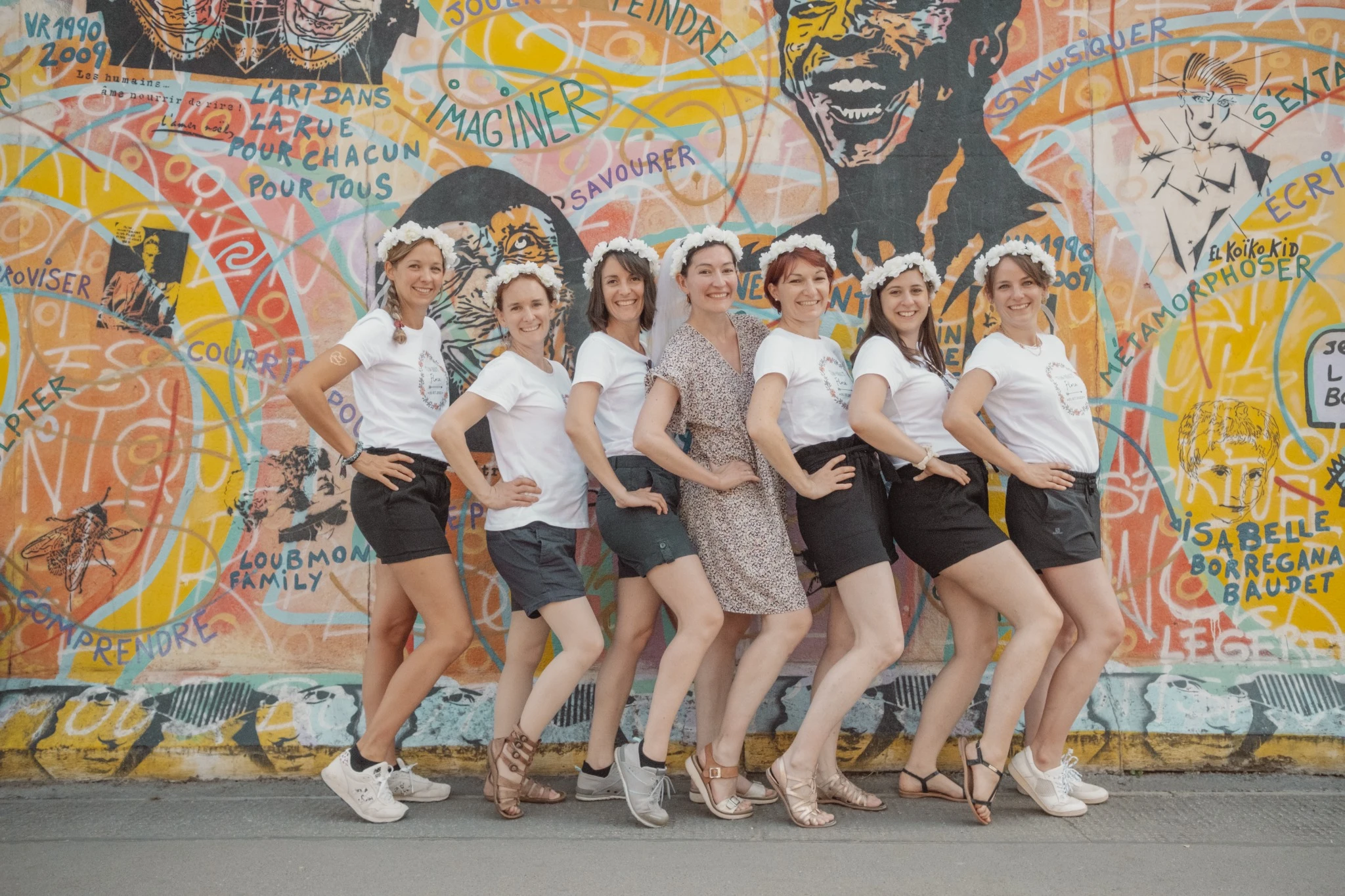 Filles en tenue EVJF à Berlin posant devant un mur coloré de l’East Side Gallery