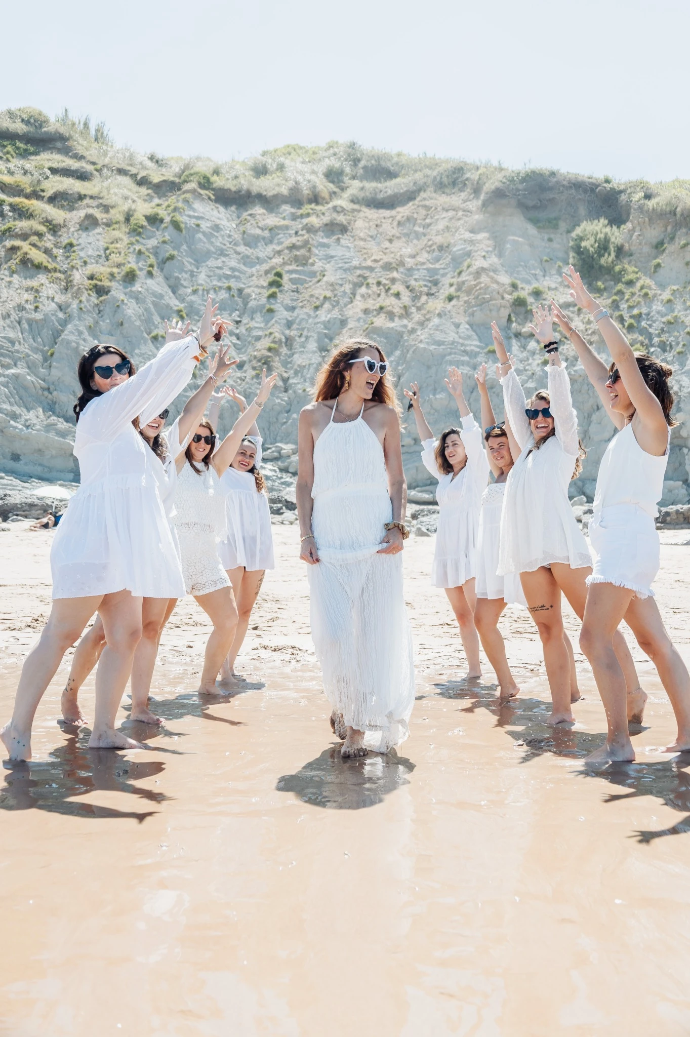 Entrée festive de la mariée entourée de ses amies en blanc sur la plage de Biarritz.