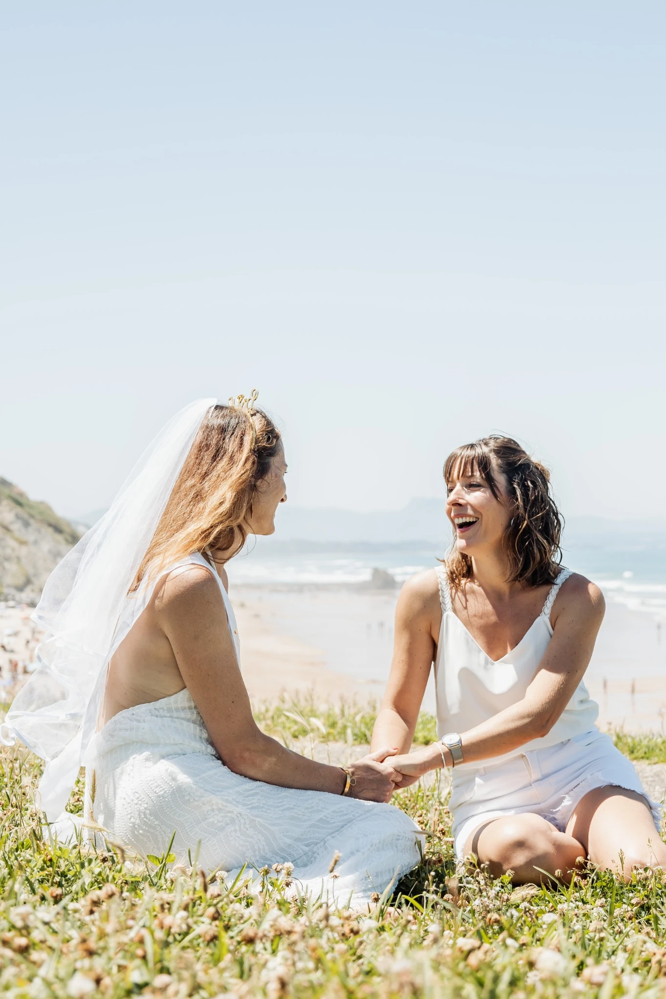 Moment complice entre la future mariée et une amie lors d’un EVJF à Biarritz, assises sur.