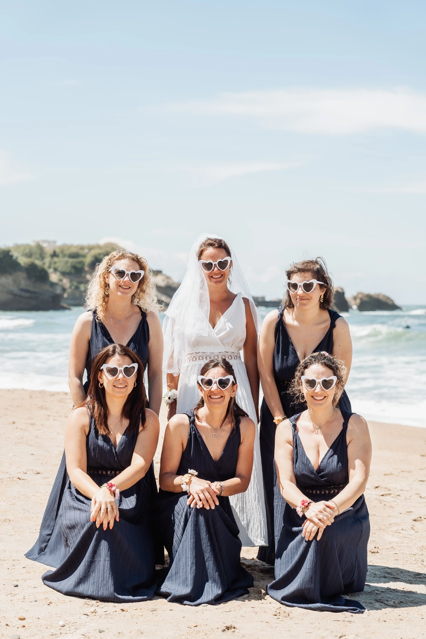 Portrait officiel de la mariée avec ses témoins en robes assorties sur la plage de Biarritz.