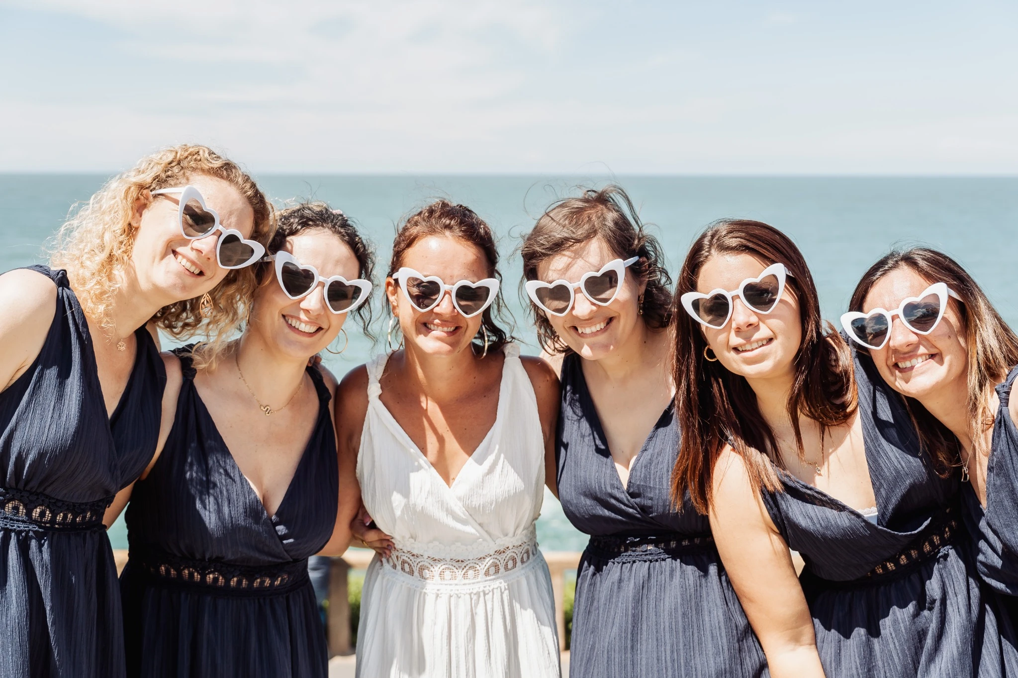 Portrait joyeux du groupe EVJF sur la côte basque à Biarritz avec la mer en arrière-plan.