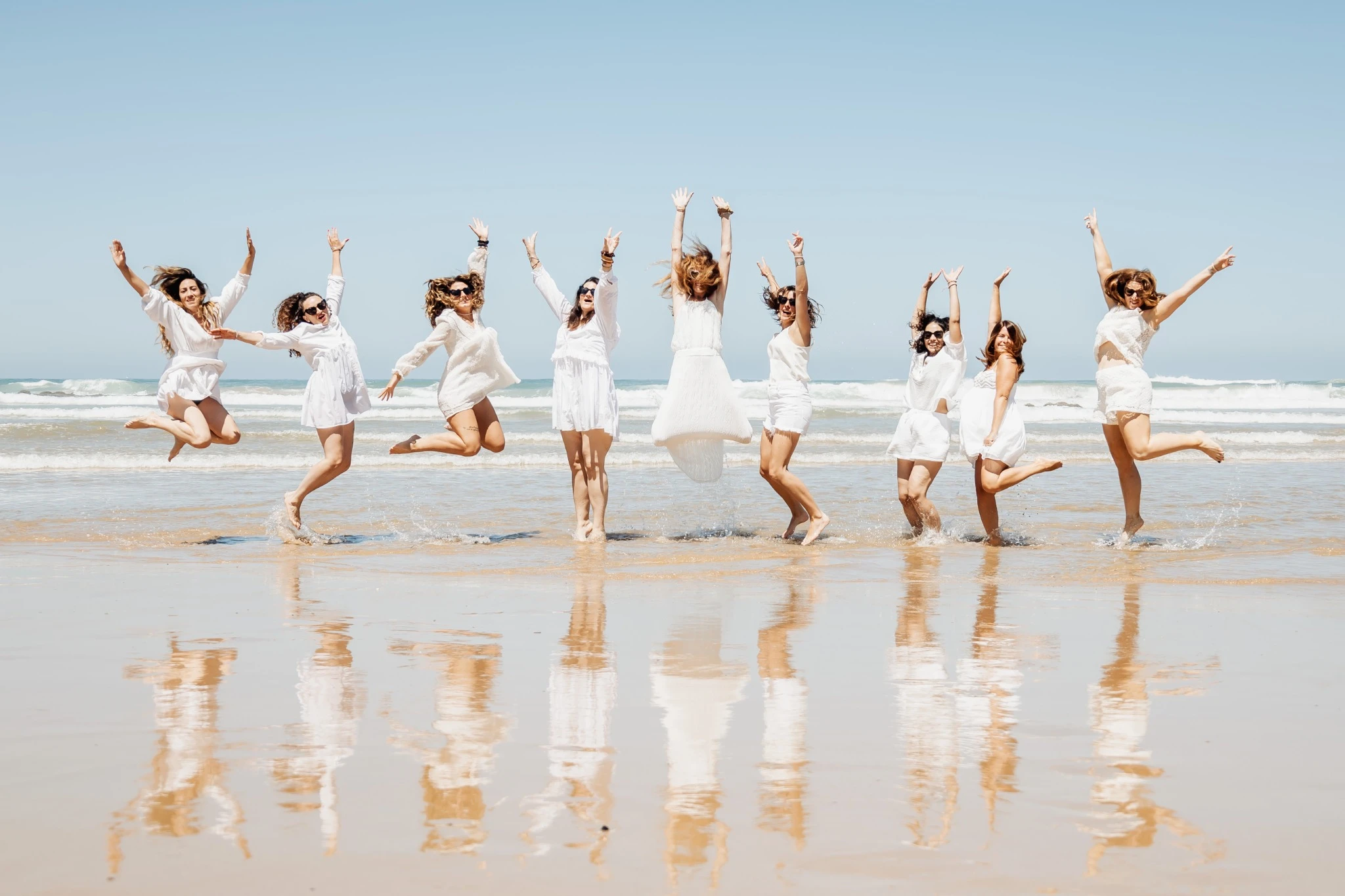 Photo de groupe sautant sur la plage de Biarritz lors d’un EVJF plein de joie.
