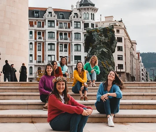 Photo de groupe EVJF devant Puppy du musée Guggenheim à Bilbao avec des tenues colorées et sourires complices