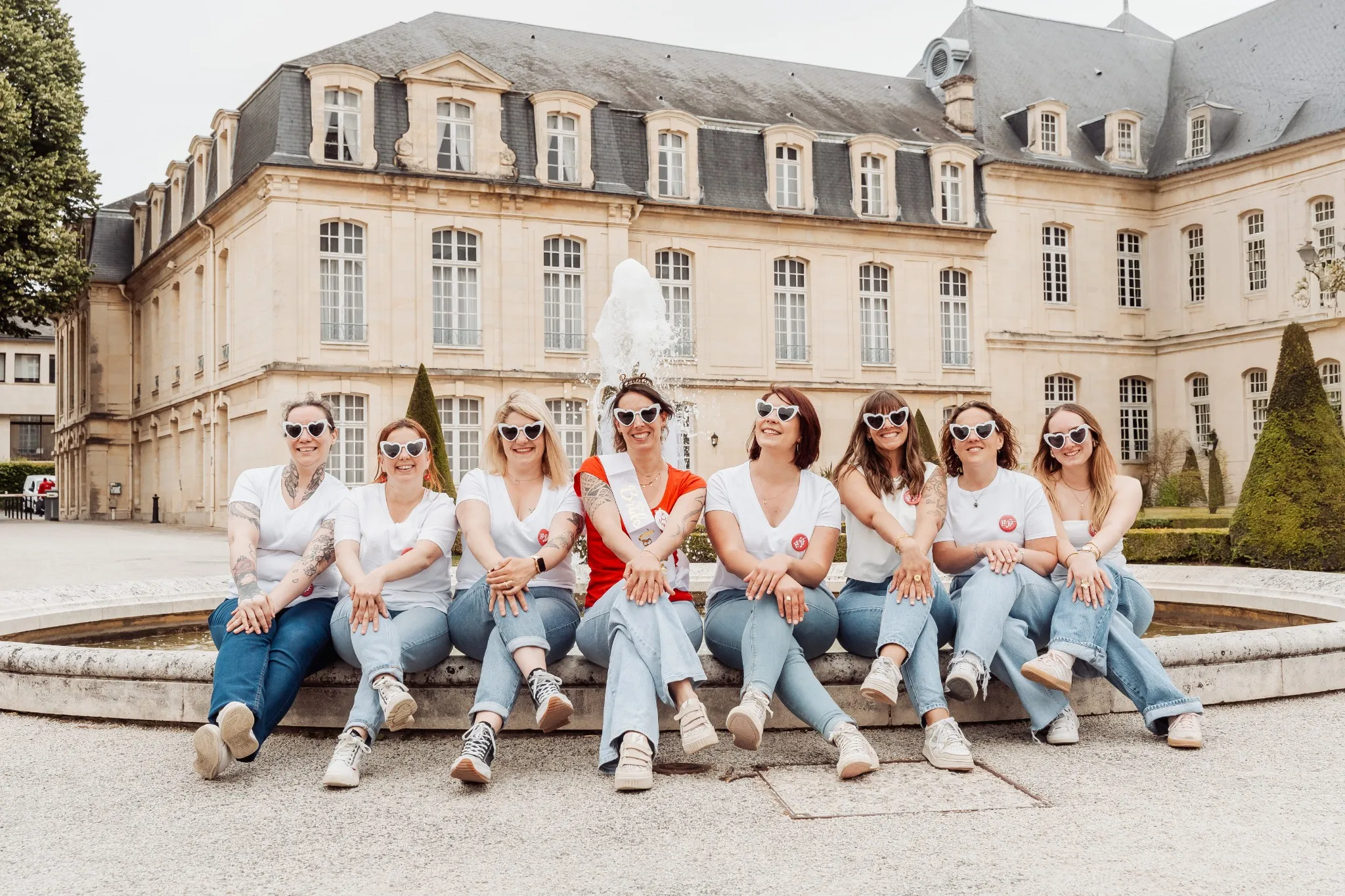 evjf-caen-fontaine-chateau-photo-groupe-classique Photo EVJF à Caen – groupe assis en ligne devant un château, ambiance élégante