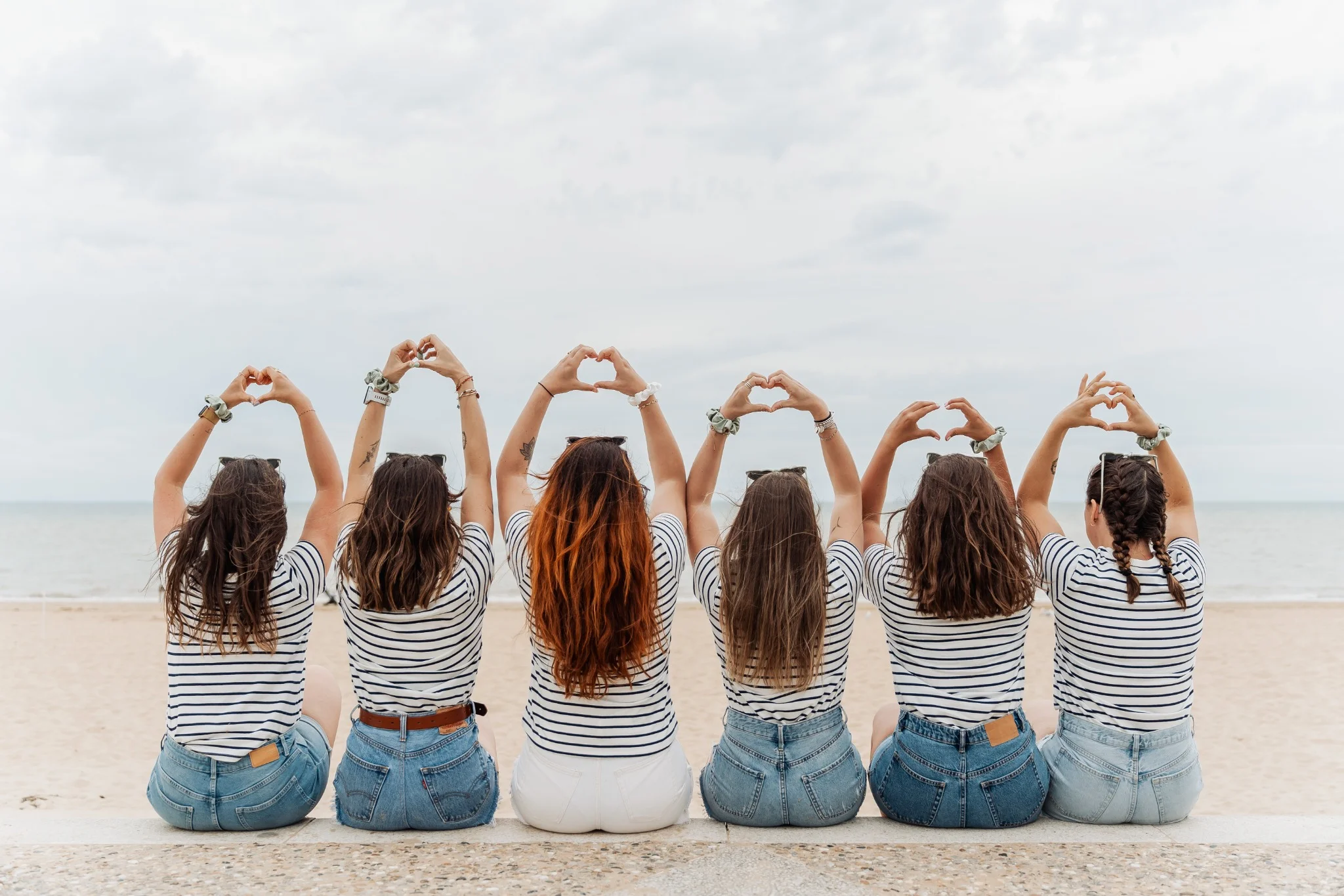 Groupe de filles en marinière faisant des cœurs avec les mains sur la plage à La Rochelle