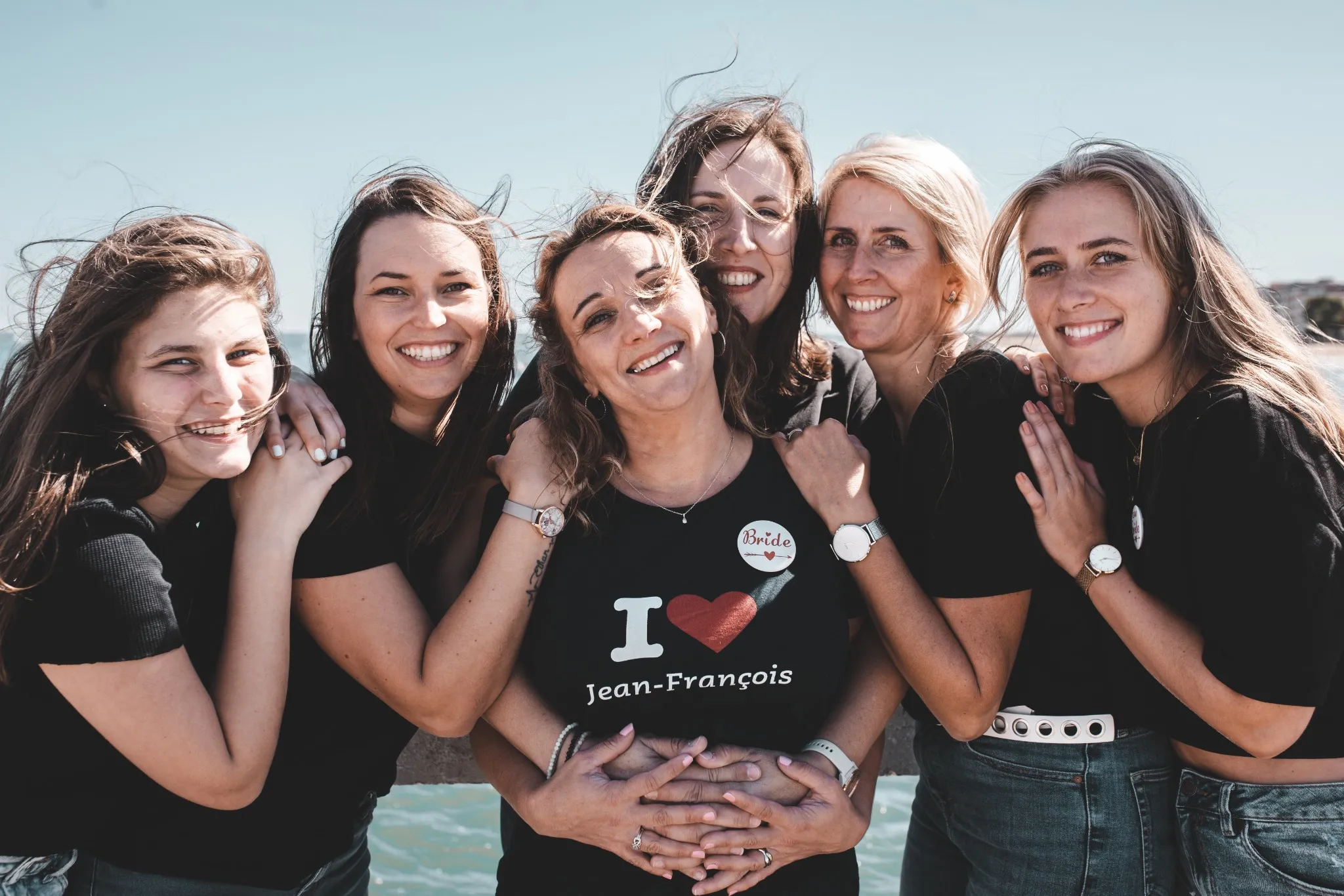 evjf-lacanau-groupe-filles-bord-de-mer Groupe de filles en noir souriantes lors d'un EVJF à Lacanau en bord de me