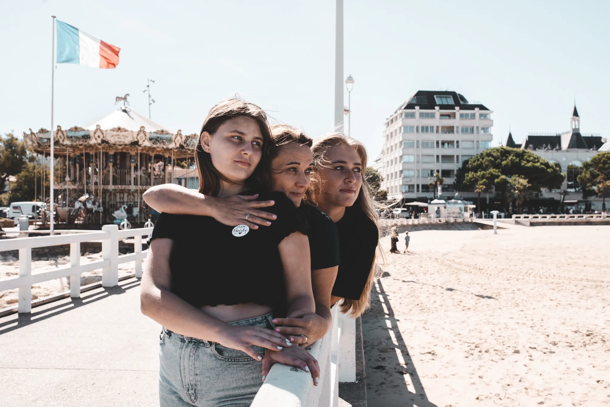 evjf-lacanau-manège-en-fond Portrait de trois femmes sur la promenade de Lacanau avec le manège en arrière-plan pendant un EVJF