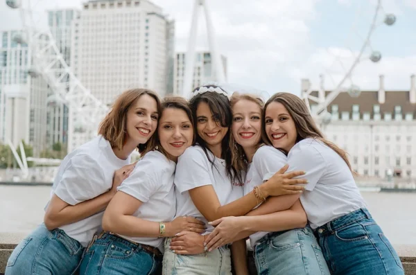 evjf-londres-london-eye-riviera Groupe de filles en t-shirts blancs lors d'un EVJF à Londres devant le London Eye
