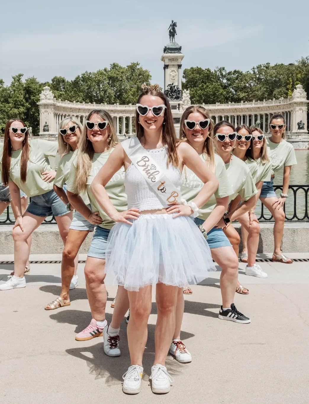 evjf-madrid-groupe-lac-palais Photo de groupe EVJF à Madrid devant le palais du parc du Retiro, toutes les participantes en t-shirt vert et lunettes cœur