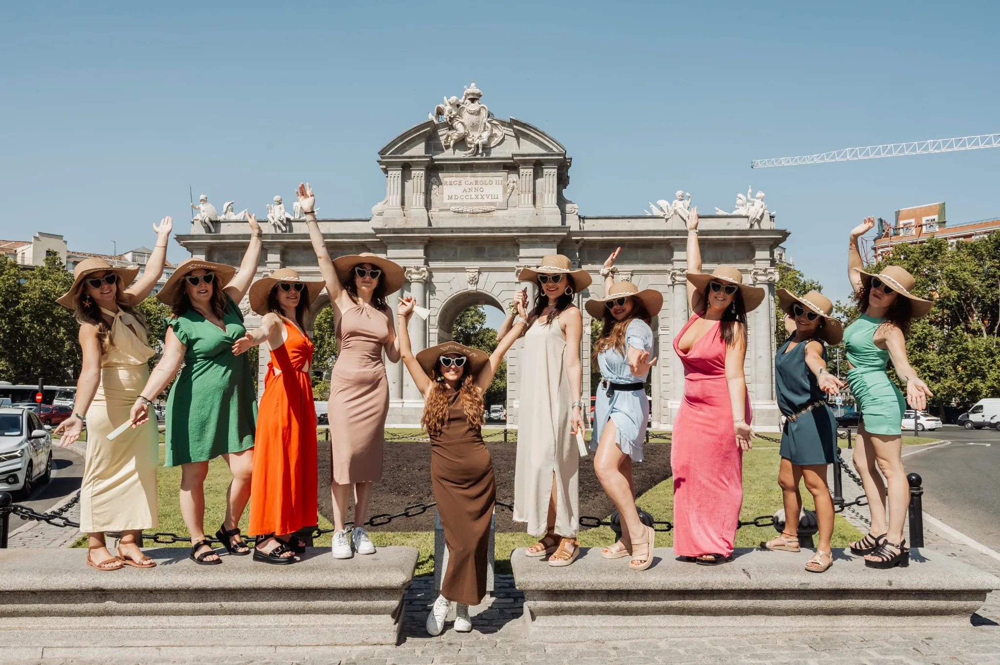 evjf-madrid-puerta-de-alcala-robe-chapeau Photo de groupe EVJF devant la Puerta de Alcalá à Madrid, toutes les filles en robe colorée et chapeau de paill