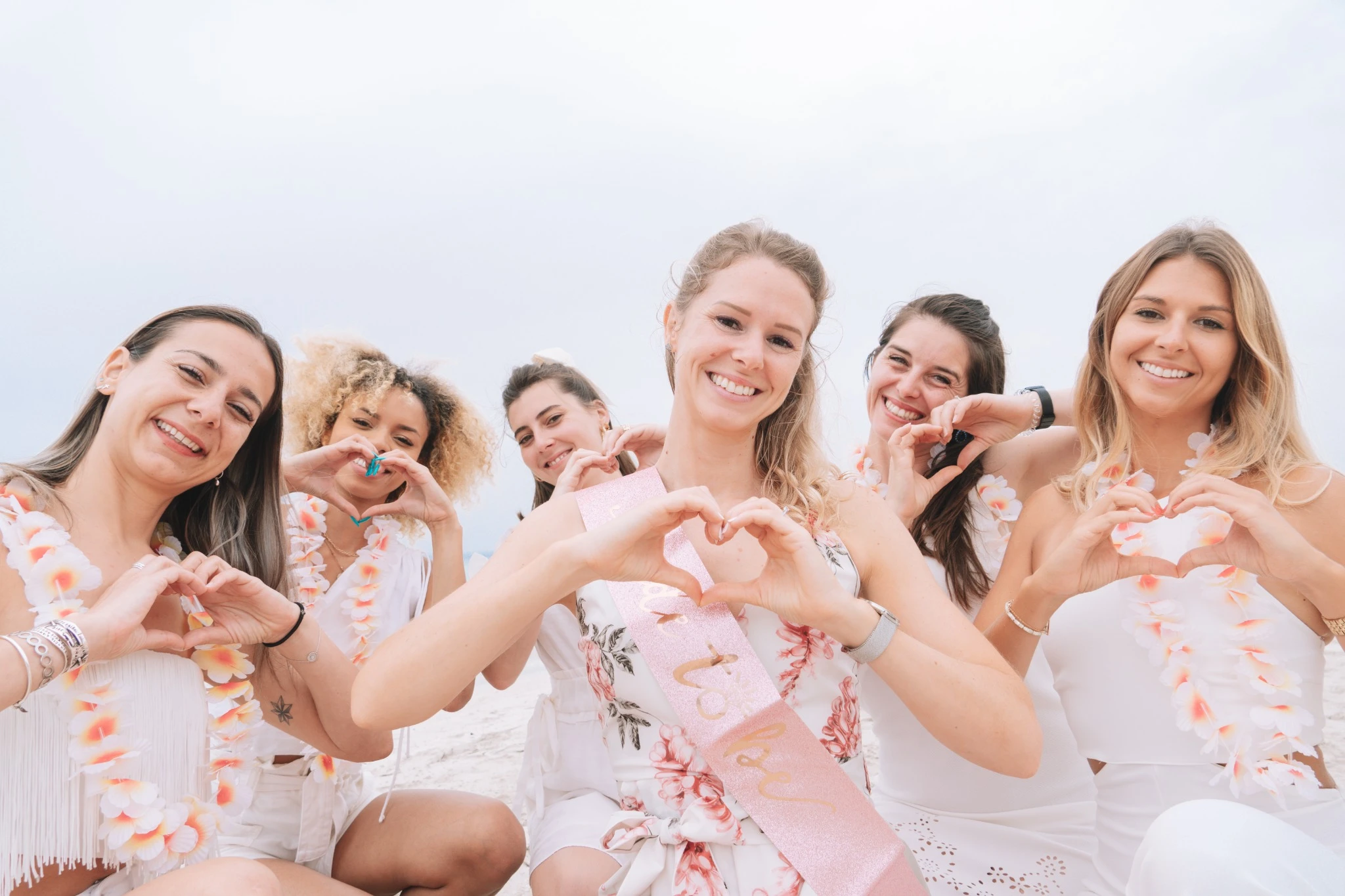 Groupe d’amies EVJF formant un cœur avec leurs mains sur la plage de Majorque