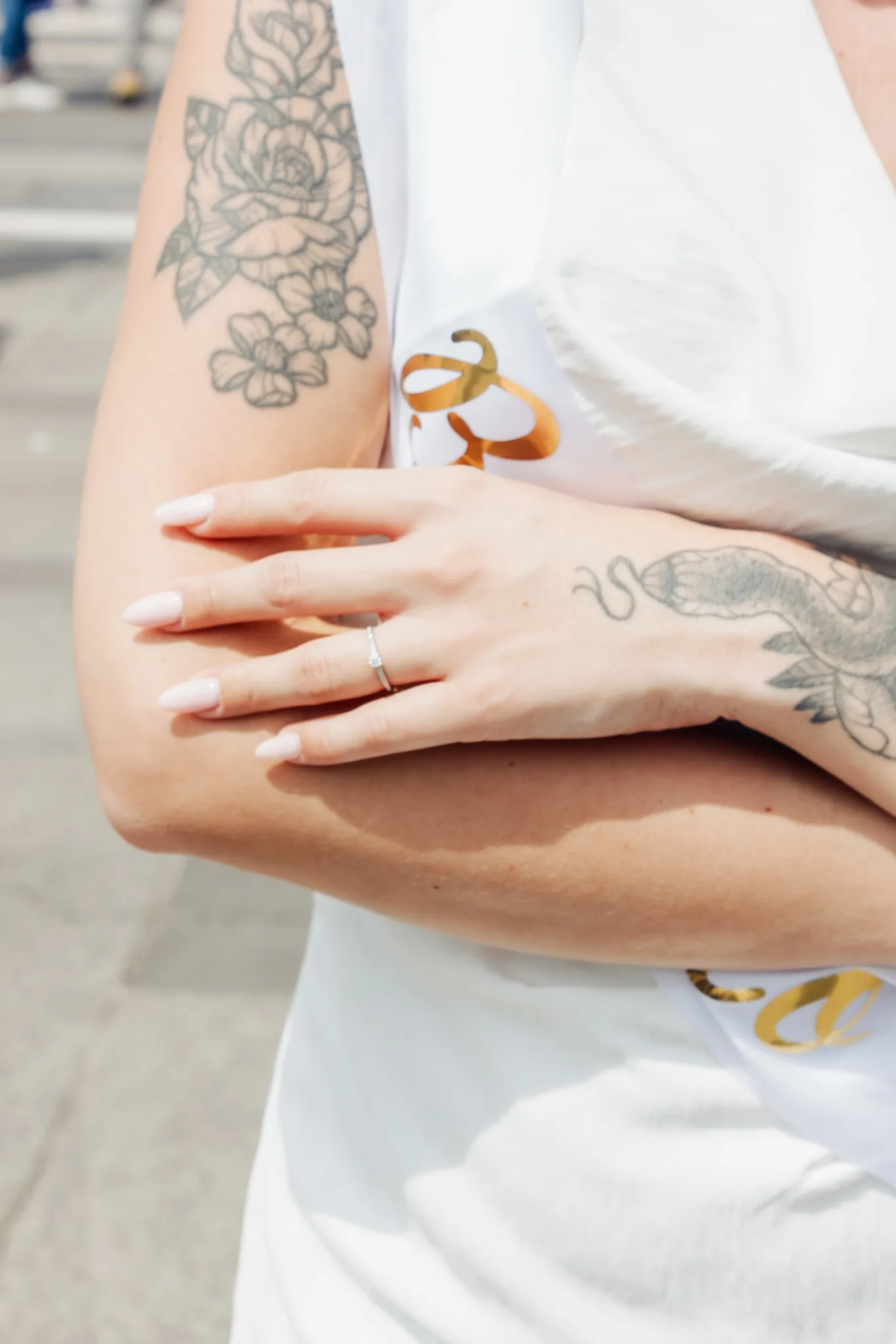 Bague de fiançailles – Gros plan futur mariée lors d’un EVJF à Milan Gros plan sur la main d’une future mariée avec une bague de fiançailles, bras croisés, tatouages visibles, lors d’un EVJF à Milan.