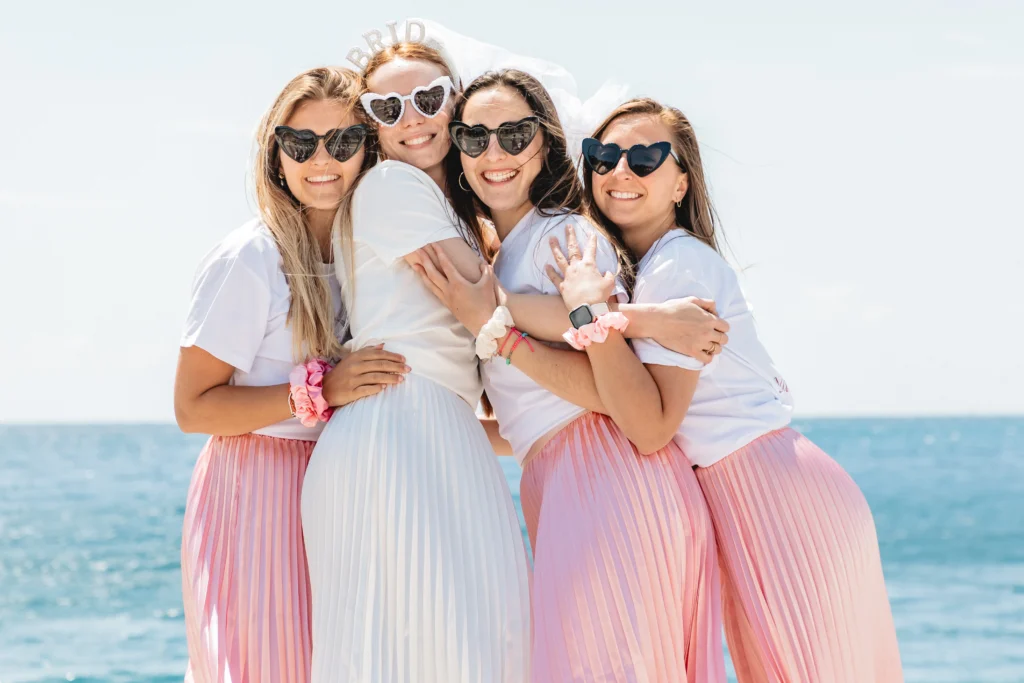 EVJF à Nice – La mariée partage un moment de tendresse avec sa team bride en jupes roses sur la plage