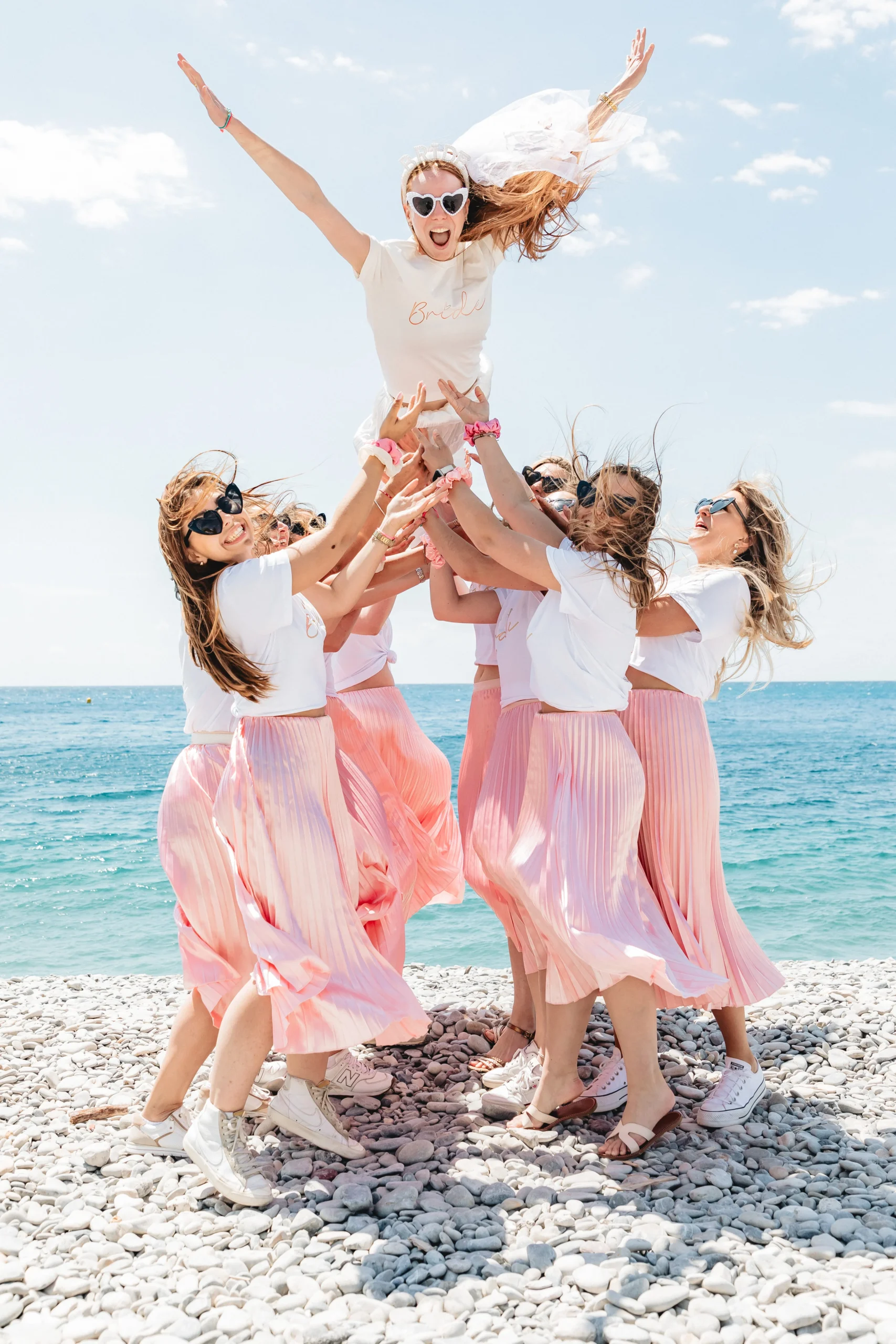EVJF à Nice – La future mariée s’envole dans les airs portée par ses amies en jupes roses face à la mer Méditerranée
