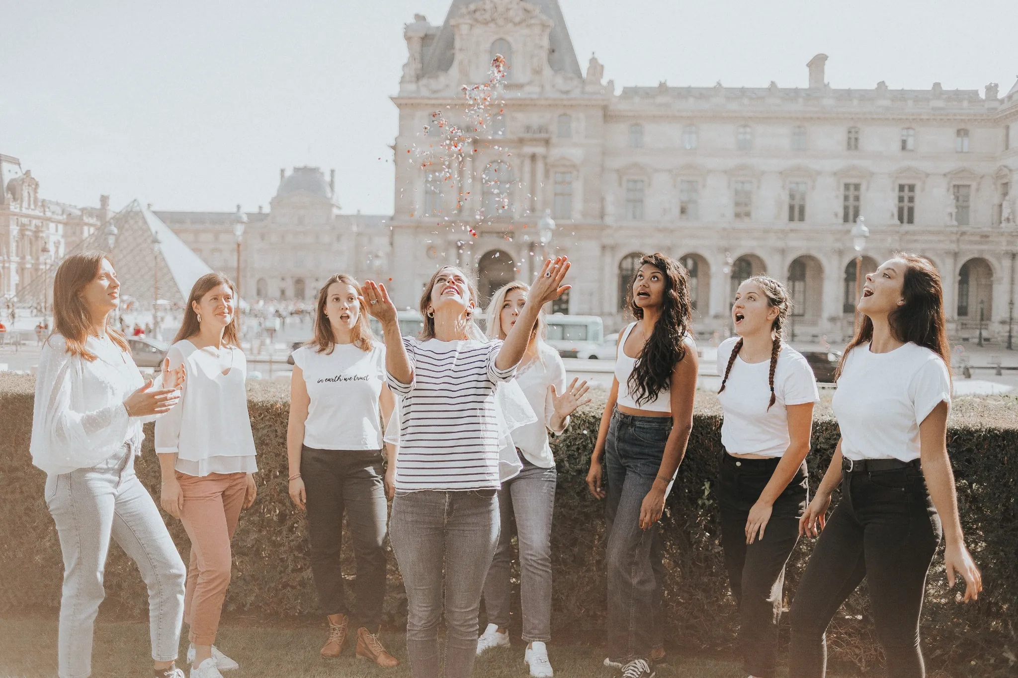 Shooting EVJF au Louvre – Instant magique entre amies avec des confettis devant la pyramide
