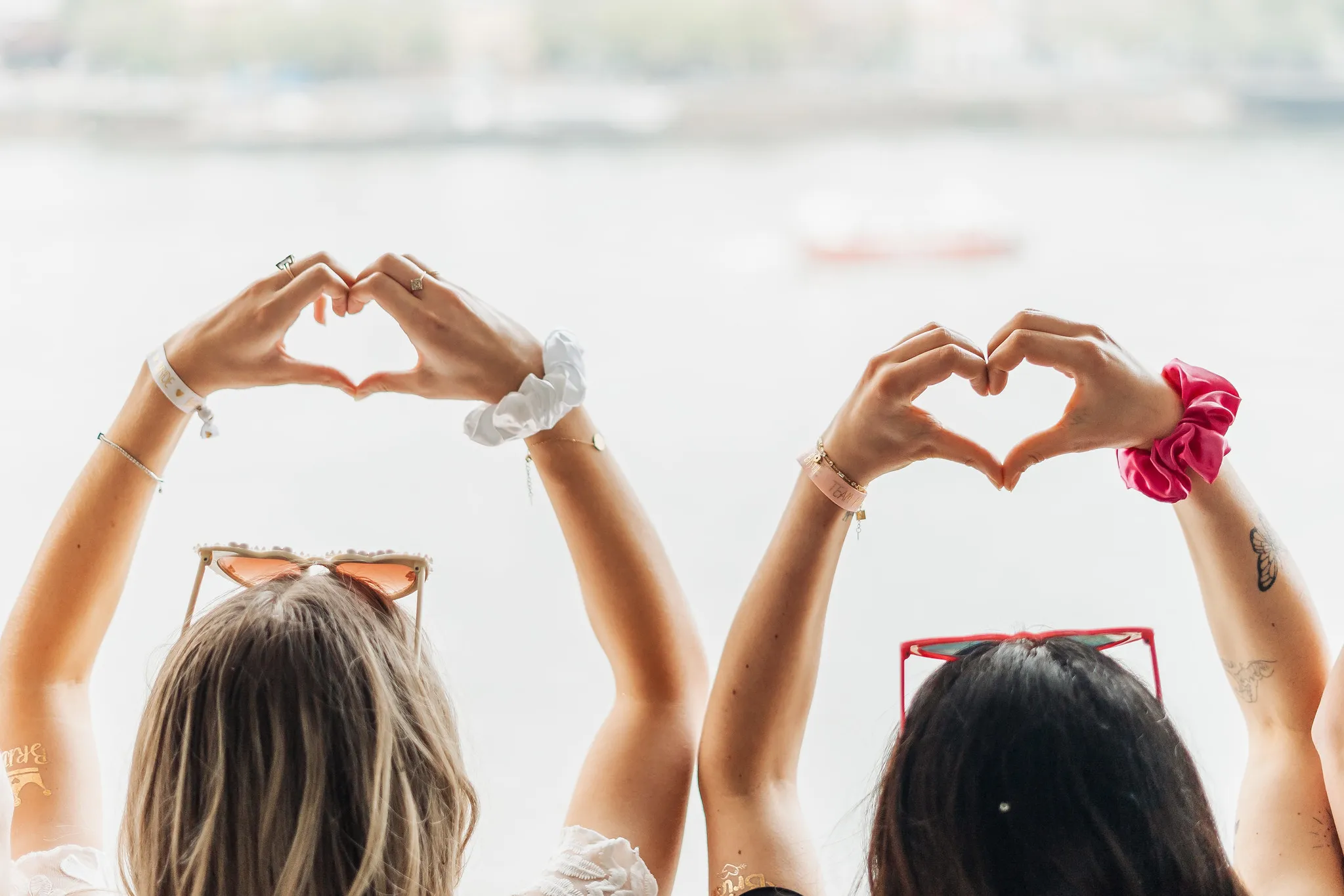 EVJF à Porto – Mains formant un cœur face au Douro Deux femmes de dos levant les bras et formant un cœur avec leurs mains, face au fleuve Douro à Porto, lors d’un EVJF.