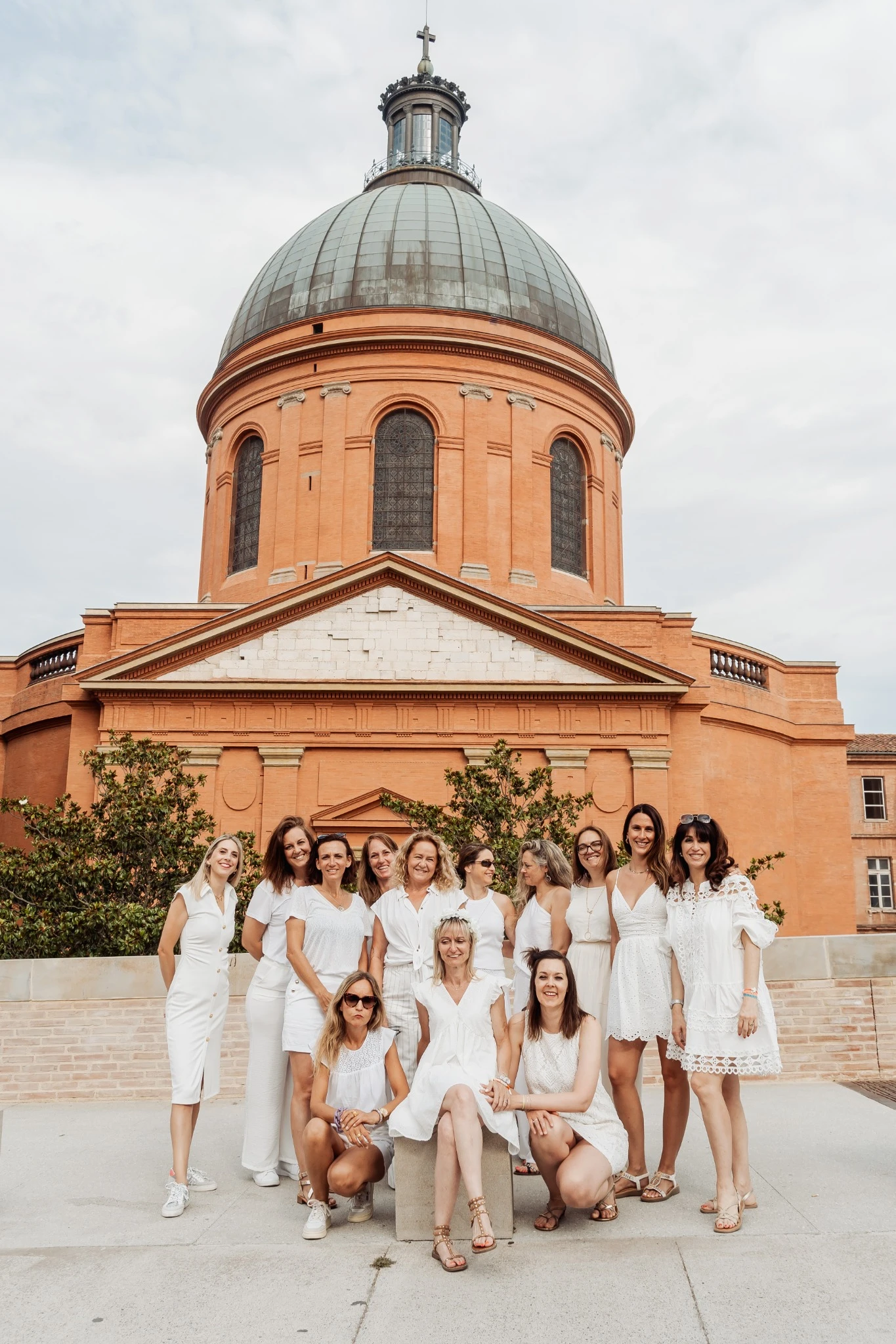 evjf-toulouse-groupe-coupole Groupe de femmes en blanc devant la coupole de La Grave à Toulouse lors d’un EVJF, ambiance joyeuse et élégante.