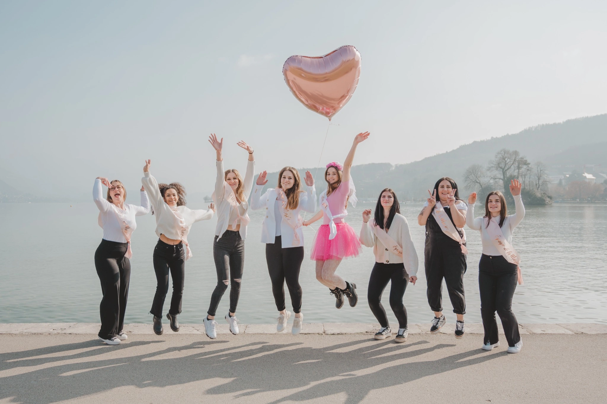 Photo de groupe sautant en l'air pendant un EVJF au bord du lac d’Annecy